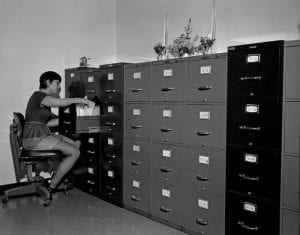 Woman filing records in a library or archives, https://oregondigital.org/catalog/oregondigital:df70ck373